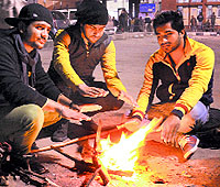 Youngsters keep warm around a bonfire at the Jalandhar railway station