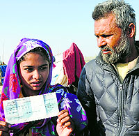 Mohd Raees daughter Gulshana shows a cheque she got during a mass wedding