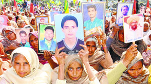 Women display pictures of their deceased family members at a dharna in Bathinda.