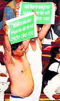 Two RLD members display placards after removing their kurtas in protest against the ruling SP government over non-payment to sugarcane farmers in Lucknow on Wednesday