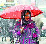 A girl tries to protect herself from snow in Anantnag on Saturday