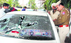 Police officers inspect a car damaged in the shootout at Sarabha Nagar market in Ludhiana.