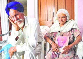 Kuldip Singhs mother holds his picture as father Ajaib Singh looks on at Amrali village in Ropar