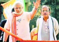BJP PM nominee Narendra Modi waves to the crowd during a road show in Varanasi on Thursday.  PTI 