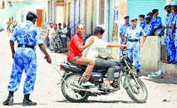 Rapid Action Force personnel tell a motorcyclist to return in curfew-bound Kishanbagh area of Hyderabad on Thursday.