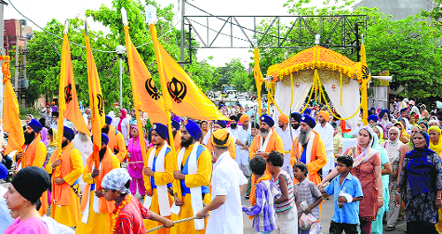 Devotees take part in a nagar kirtan to mark the martyrdom anniversary of Guru Arjan Dev in Mohali on Friday.