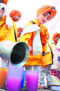 Students serve sweetened milk to commuters on the occasion of Shri Guru Arjun Dev’s Shaheedi Purab on Saturday