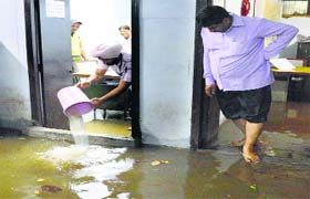 A government employee drains out rainwater from his office in the basement of the Mini-Secretariat