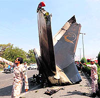 Iranian Revolutionary Guards and security forces stand next to the remains of a plane that crashed near Tehrans Mehrabad airport on Sunday