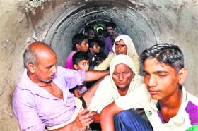 Villagers take shelter in a sewerage pipe at Kathmaria village in the RS Pura sector of Jammu district on Sunday