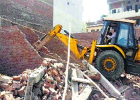 Taken to task: Building branch officials of the Municipal Corporation razed 10 shops at Fatehgarh Mohalla, Gandhi Nagar, on Monday