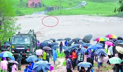 An Army rescue vehicle tries to pull out a bus (encircled) submerged in the raging waters after it was swept away at Nowshera in Rajouri district on Thursday.