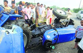 Commuters look at the damaged tractor near Jagera village in Mandi Ahmedgarh