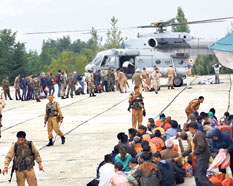 Stranded people board an IAF MI-17 V5 helicopter at Nehru helipad in Srinagar as others await their turn.