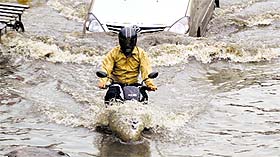 A motorcyclist makes his way through a flooded road near Domoria Bridge;
