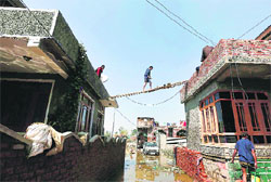 A man walks on a ladder carrying food and water to his house in Srinagar on Monday. Reuters