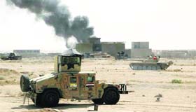 A convoy of Iraqi security forces is seen during a patrol, as smoke rises from clashes with Is militants on the outskirts of Ramadi.