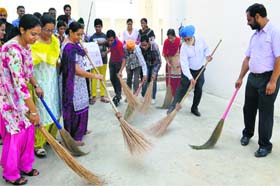 Special Secretary, Secondary Education, Gurdeep Singh and school staff clean the floor at the Senior Secondary Residential School for Meritorious Students