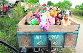 Villagers sit in a tractor- trailer as they wait to be shifted to a safe area following shelling by Pakistan at Chilyari village in Samba, Jammu, on Wednesday