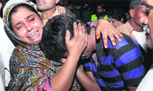A woman consoles a man mourning for his relative killed in the bomb explosion, in Lahore. 