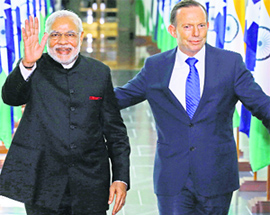 Prime Minister Narendra Modi waves as he walks with his Australian counterpart Tony Abbott as they leave Parliament House in Canberra on Tuesday.