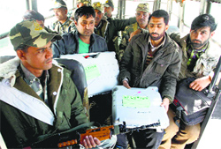 Security personnel and election officials carry electronic voting machines to a polling station in Doda on Monday.