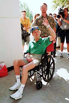 Australian tennis great Rod Laver, 60 gives a wave as his son Rick pushes his wheelchair after the tennis great was discharged from UCLA Medical Centre in the Westwood section of Los Angeles on Thursday. Laver suffered a moderate stroke on July 27 during the taping of a television interview.—AP/PTI