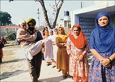 Ninety-year-old Mahesh Dutt is carried by a party worker to cast his vote at the Ghurial village polling booth in the Punjab Assembly byelection for the Adampur seat on Wednesday.