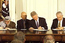 President Bill Clinton, Palestinian leader Yasser Arafat and Israeli Prime Minister Benjamin Netanyahu sign the West Bank accord