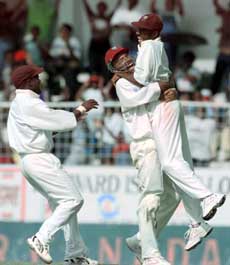 Nehemiah Perry of the West Indies (right) is embraced by Jimmy Adams (center) after Perry made a throw to get Justin Langer of Australia run out for 51 during the fourth and final test match