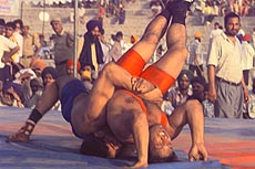 Abdul Majid of Pakistan in red costume lying to wriggle out of the grip of Bhim Singh of Rajsthan
