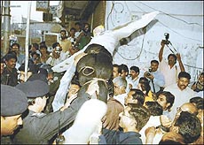 Police officers try to snatch effigy of Prime Minister Nawaz Sharif from supporters of Benazir Bhutto
