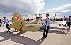 Airfield crew pulls a World War II Po-2 biplane at the international MAKS-99 air show 
