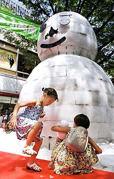 Japanese girls play around a snowman displayed at Tokyo's famous Ginza shopping district. 