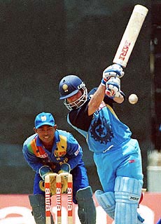 Indian batsman Sachin Tendulkar drives the ball as Sri Lankan wicket keeper Romesh Kaluwitharana looks on during an Aiwa Cup limited over cricket match between India and Sri Lanka
