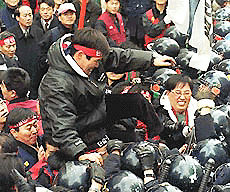 A South Korean worker kicks the head of a riot policeman during a clash in front of the headquarters of the ruling party, National Congress for New Politics, in Seoul, Tuesday.