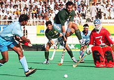 Pakistani Ahmed Alam jumps in the air, diverts the attack of Indian player Dilip Tirkey (left) during the sixth hockey test in Karachi on Thursday.