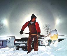 DES MOINES : Ice crystals in the air form "sun dogs" behind Kyle Sorensen, of Waukee, Iowa as he digs out from the weekend snow storm, Sunday morning. Near zero temperatures and high winds have made for deadly wind chill readings across the upper Midwest  AP/PTI
