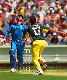 England's Graeme Hick looks up after hitting the ball high in the air, to be caught by wicket-keeper Adam Gilchrist, for three off Damien Fleming (right) as England choose to bat first against Australia at the Melbourne Cricket Ground on Friday — AP/PTI