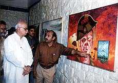 Union Home Minister L.K. Advani at an exhibition of paintings on Kargil by an Ahmedabad-based painter, Mohsin Shaikh (right), which opened in New Delhi on Wednesday.