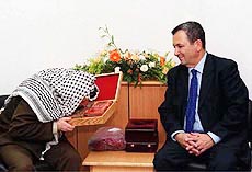 Israeli Prime Minister Ehud Barak watches as Palestinian leader Yasser Arafat kisses the Koran