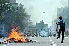 A student protestors throws a stone at riot police near Tehran University