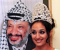 Sheikha Salim, a student from the Golan Village of Majd Al-Kurum, stands along side a portrait of Palestinian leader Yasser Arafat, after winning the peace and love beauty contest which was held for the first time in the West Bank city of Ramallah on Monday.