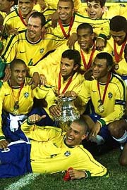 Brazilian soccer ace Ronaldo (on ground) makes a thumb up, as he is surrounded by teammates and the trophy, after defeating Uruguay 3-0 to clinch the America's Cup