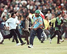 An Indian cricket fan runs away with a stump.