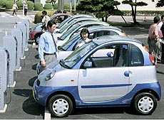 Toyota Motor Corp. employees examine small two-seater electric cars lining up for the carmaker’s experiment of using such vehicles for 300 workers’ commuting and short trips at Toyota headquarters’ testing site in central Japan.