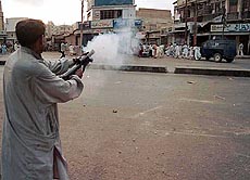 A plainclothed policeman fires up a tear gas to disperse fighting demonstraters on Sunday in Karachi. Militants of two rival Sunni Muslims sects clashed while marching together in a street to celebrate the birth anniversary of Prophet Mohammad.