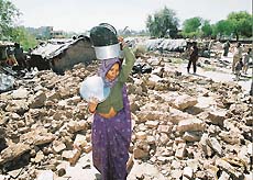 A jhuggi-dweller collects her household items after her jhuggi was pulled down as part of a demolition drive in Sector 12-A of Panchkula on Saturday
