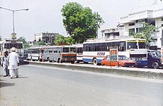Buses parked in front of the bus stand are a traffic hazard
