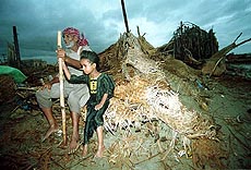 Residents of Gharo, 40 kilometers east of Karachi sit on debris of his house destroyed by heavy cyclone, Thursday. A cyclone slammed Pakistan coastal area packing winds of up to 170 mph, causing tidal waves that buried thousands of homes and left thousands of people missing.